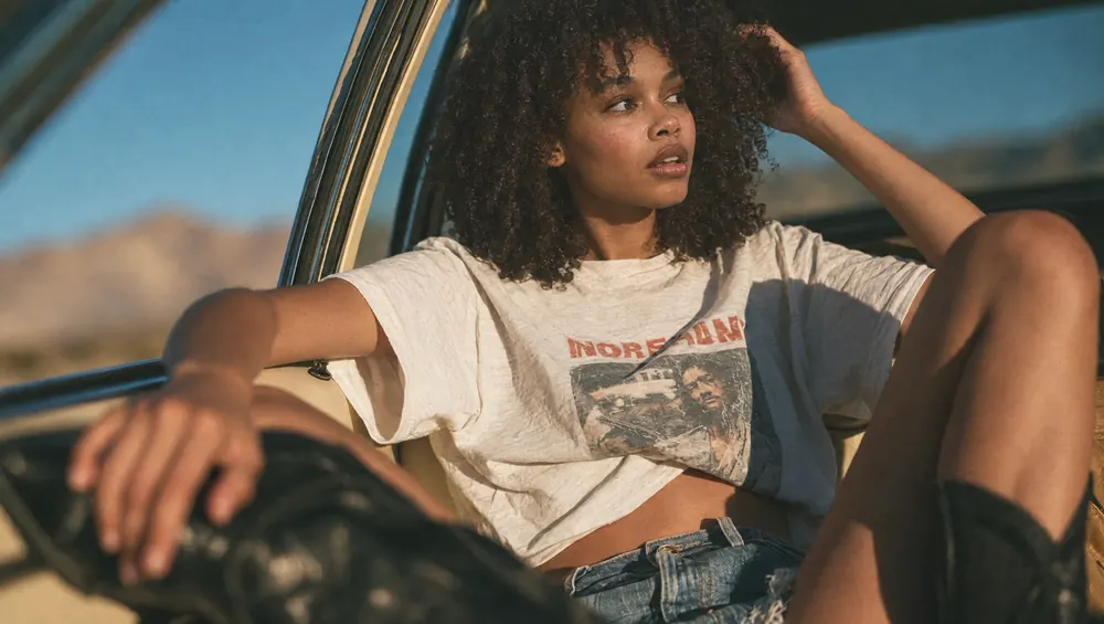 Chica sentada en la ventanilla de un coche en el desierto