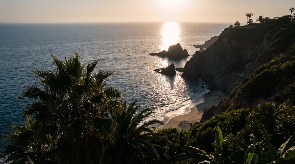 Costa con palmeras y el sol sobre el mar, vista aérea